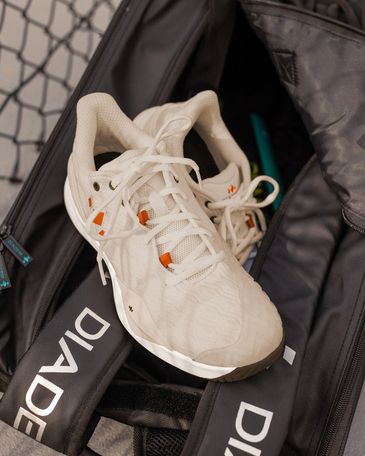 A pair of Diadem Court Burst shoes in Desert Sun resting in a Diadem bag